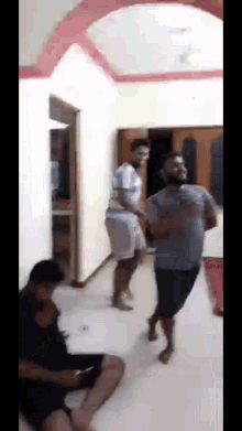 a group of men are dancing in a living room while a woman sits on the floor .