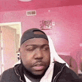 a man wearing a baseball cap looks at the camera in front of a pink wall that says " available "