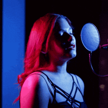 a woman with red hair singing into a microphone in a dark room