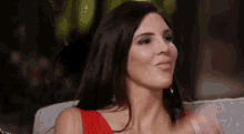 a woman in a red dress is sitting on a couch and making a face .
