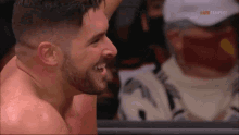 a man with a beard is laughing in a wrestling ring while a man in a white hat watches .