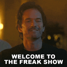a man with a beard is smiling and says welcome to the freak show .