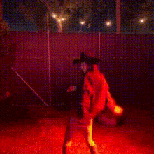 a man in a cowboy hat is standing in front of a fence