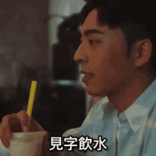 a man drinking a drink with a yellow straw with chinese writing on the bottom