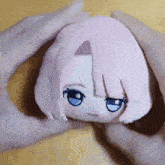 a person is holding a stuffed animal with pink hair and blue eyes .