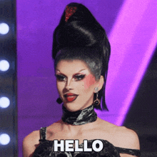 a drag queen says hello on a stage
