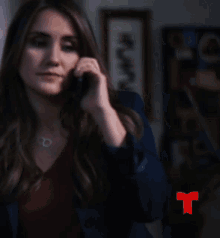 a woman talking on a cell phone with a red t on the sleeve