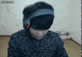 a man wearing headphones and a headband is sitting in front of a computer screen .