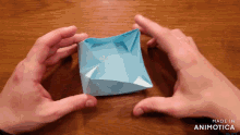 a person is holding a piece of blue paper that says made in animotica on the bottom