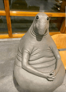 a statue of a sea otter sitting on a chair in front of a window
