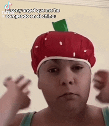 a woman wearing a strawberry hat is making a funny face .