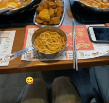 a pot of spaghetti sits on a table next to a menu