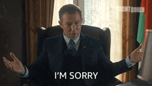 a man in a suit says i 'm sorry in front of a window