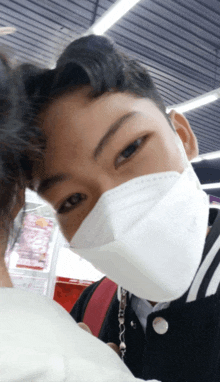 a young man wearing a white face mask with a black jacket