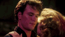 a close up of a man 's face with a woman 's arm around his neck