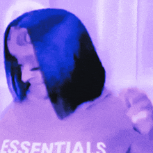 a woman wearing a purple shirt that says essentials on it