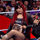 a woman with red hair is sitting in a wrestling ring with usa written on the bottom