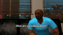 a man in a blue shirt is sitting on a couch and talking about something