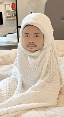 a man is wrapped in a white blanket with his face wrapped in it