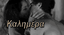 a black and white photo of a man and woman kissing with the word kalimera in the corner