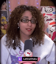 a woman with curly hair is wearing glasses and holding a microphone with latinaotaku written on it