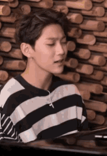 a young man in a striped shirt is playing a piano
