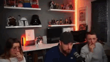 a group of people are sitting in front of a microphone in a room with shelves filled with toys .