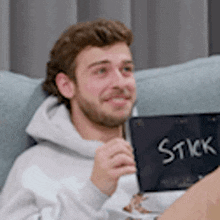 a man is sitting on a couch holding a stick in his hand .