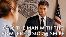a man in a suit and tie is talking to a police officer with powdered sugar on his face .