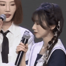 a woman is holding a microphone next to another woman who is holding a microphone .