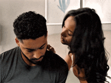 a woman is touching a man 's ear while they are sitting next to each other