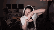a woman wearing headphones has a sub goal of 83/150 on her screen