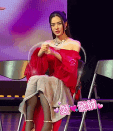 a woman in a red dress sits in a chair with chinese writing on it