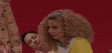 a woman with curly blonde hair wearing a headband looks at the camera