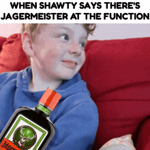 a bottle of jagermeister sits next to a boy on a couch