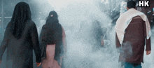 a group of people are walking through a foggy area with the letters hk on the bottom
