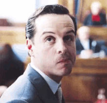 a man in a suit and tie is making a funny face in a courtroom .