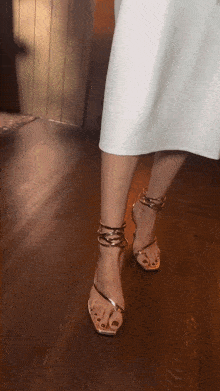 a woman in a white dress is wearing a pair of gold sandals