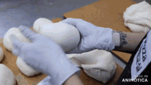 a person wearing gloves is holding a ball of dough in their hands with the words made in animotica below them