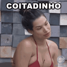 a woman in a red bikini is sitting in front of a wall with the word cotadinho written on it .