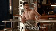 a shirtless man is wrapped in a towel in a kitchen and holding a bottle of water .