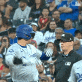 a baseball player in a dodgers uniform is talking to a referee .