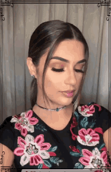 a woman wearing a choker and a floral shirt looks at the camera
