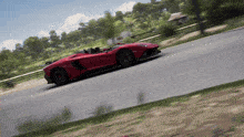 a red sports car is driving down a road with trees in the background