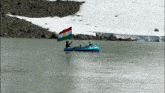 a man in a blue raft holds a kurdish flag