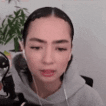 a woman wearing headphones is sitting in front of a microphone and looking at the camera .