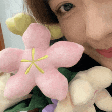 a close up of a woman holding a pink flower with a yellow center