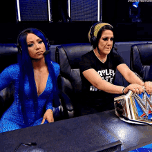 two female wrestlers are sitting at a table with a wwe championship belt