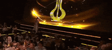 a group of people sitting at a table in front of a stage with a yellow light behind them