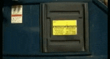 a man is sticking his head out of a dumpster with a yellow sign on it .
